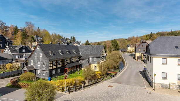 A residential street with houses, a clear sky, and a road curving through the scene. - Holiday Apartment in the Former Manor 'Bergblick' with Garden and Wi-Fi (Wurzbach)