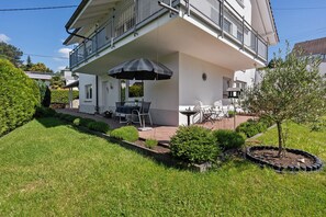 A two-story building with a balcony, outdoor seating, and a small tree. - Apartment 'Millot' with Private Terrace and Wi-Fi (Gernsbach)