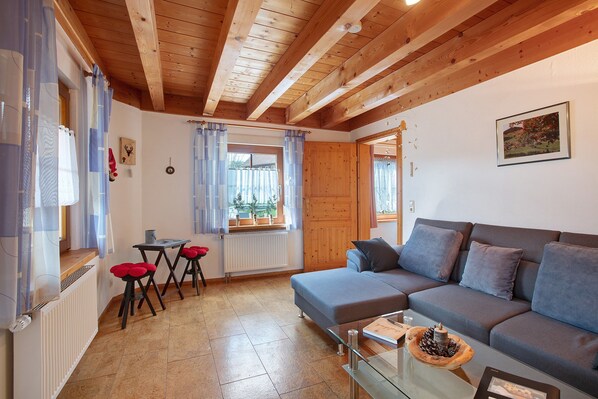 Ein gemütliches Wohnzimmer mit einer Couch, einem Glastisch und einem Essbereich mit Tisch und Stühlen.