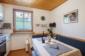 Ein Essbereich mit einem Tisch für zwei Personen, einem Fenster, einer Uhr und einem gerahmten Bild an der Wand.