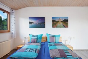Un lit double avec une literie à motifs, une table de chevet avec une lampe et deux tableaux encadrés au mur.