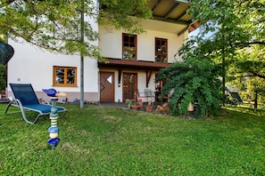 Une maison à deux étages avec un porche à l’avant, une pelouse et du mobilier d’extérieur.