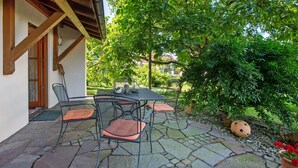 An outdoor patio with stone flooring, metal chairs, a table, and a wooden pergola. - Apartment 'Nussbäumle' with Private Terrace, Shared Garden and Wi-Fi (Rheinfelden (Baden))