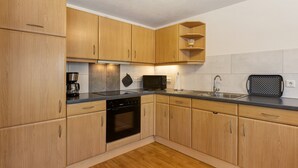 Een moderne keuken met houten kastjes, een inbouwoven, een magnetron en een waterkoker.