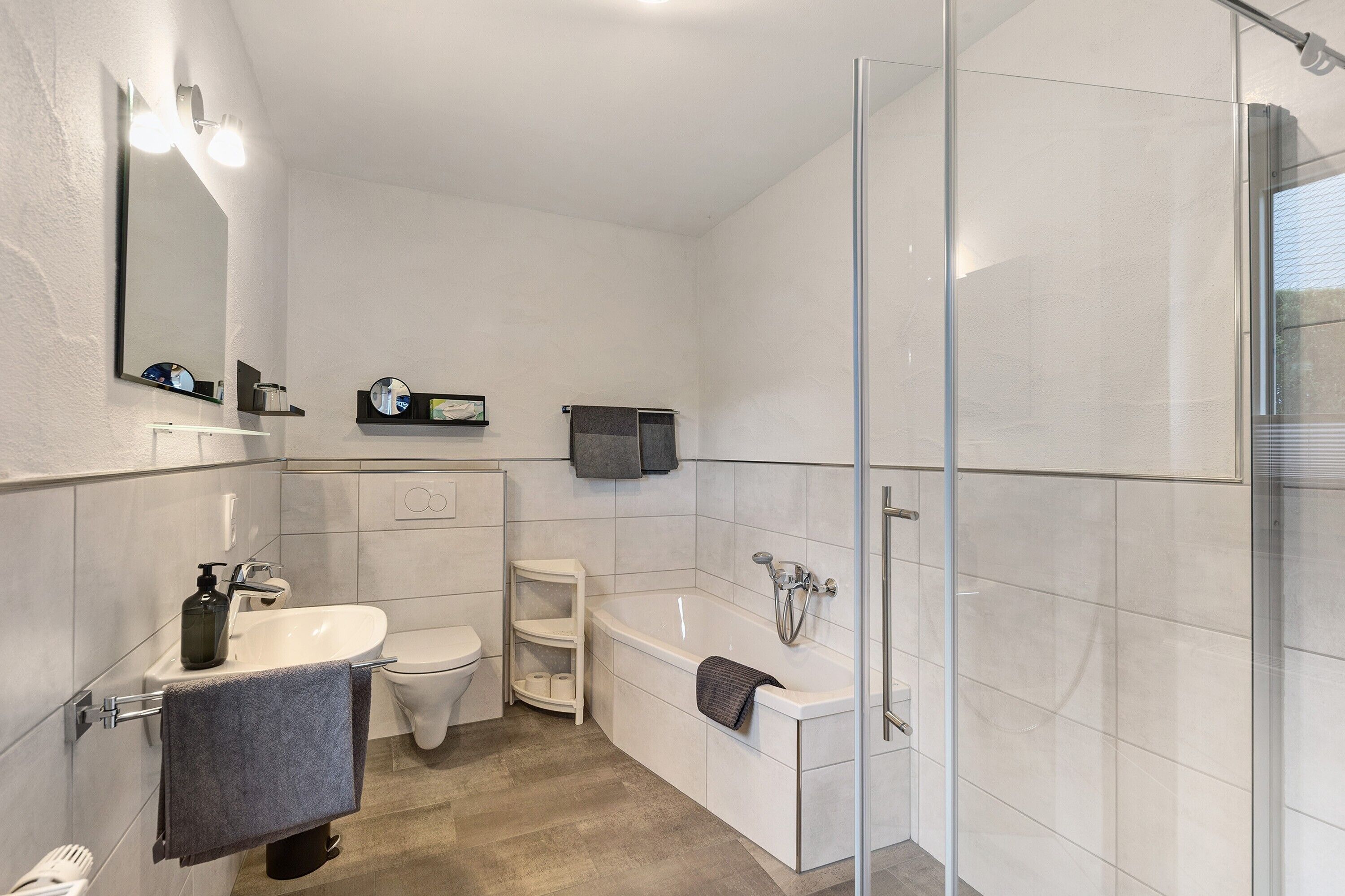 Un bagno moderno con doccia vetrata, lavandino bianco e water.