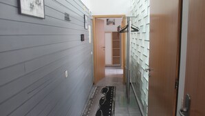 Un pasillo con un tapete estampado, una puerta de madera y un armario con ropa colgada.
