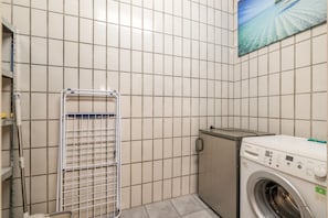 A laundry room with a Bosch washing machine, a drying rack, and a tiled wall.