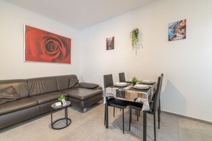 A modern living space with a sofa, a dining table with chairs, and artwork on the walls.