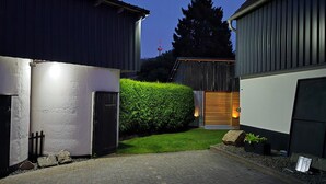 A modern building with a paved driveway, a wooden door, and a well-maintained hedge.