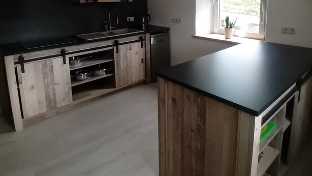 A kitchen with a central island, wooden cabinets, a stove, and a window with a view. - Holiday Home 'Haus' with Shared Terrace, Shared Garden and Wi-Fi (Kleinlangenfeld)