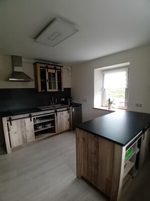 Une cuisine dotée d’un îlot central, de meubles en bois, d’une cuisinière et d’une fenêtre offrant une belle vue.