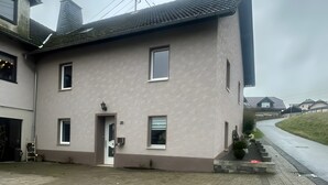 A two-story building with a flat roof, a small front porch, and a paved driveway. - Holiday Home 'Haus' with Shared Terrace, Shared Garden and Wi-Fi (Kleinlangenfeld)