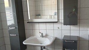 A modern bathroom with a white sink, a mirror, and a dark cabinet. - Holiday Home 'Haus' with Shared Terrace, Shared Garden and Wi-Fi (Kleinlangenfeld)