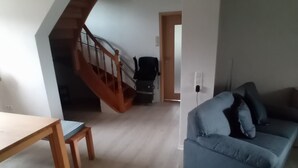 A spacious living area with a wooden staircase, a sofa, and a dining table. - Holiday Home 'Haus' with Shared Terrace, Shared Garden and Wi-Fi (Kleinlangenfeld)