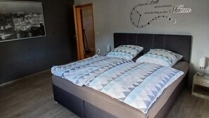 A bedroom with a bed, a wall clock, a door, and a framed picture. - Holiday Home 'Haus' with Shared Terrace, Shared Garden and Wi-Fi (Kleinlangenfeld)