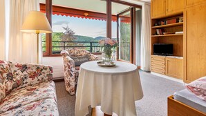 Une pièce comprenant un canapé, une table avec un vase, un téléviseur et une bibliothèque.