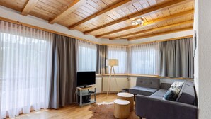 A modern living room with a wooden ceiling, a sofa, a TV, and a lamp.