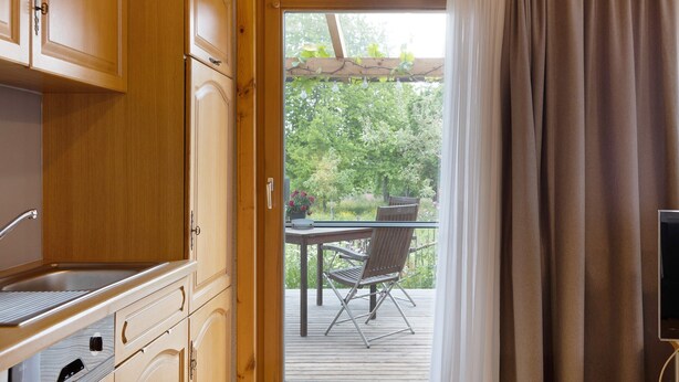 A kitchen with wooden cabinets, a built-in oven, and a window overlooking a garden.