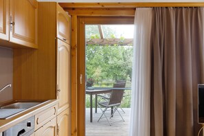 A kitchen with wooden cabinets, a built-in oven, and a window overlooking a garden. - Holiday Home 'Auszeit' with Mountain View, Private Terrace and Wi-Fi (Donaueschingen)
