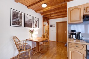 A wooden dining table with chairs, a coffee maker, and framed pictures on the wall. - Holiday Home 'Auszeit' with Mountain View, Private Terrace and Wi-Fi (Donaueschingen)
