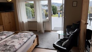 Un dormitorio con cama, una silla, un televisor y vistas al exterior.