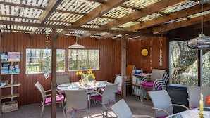A wooden interior with a round table, wicker chairs, and a bookshelf. - Apartment 'Luv Und Lee' with Private Terrace, Shared Garden and Wi-Fi (Schülp)