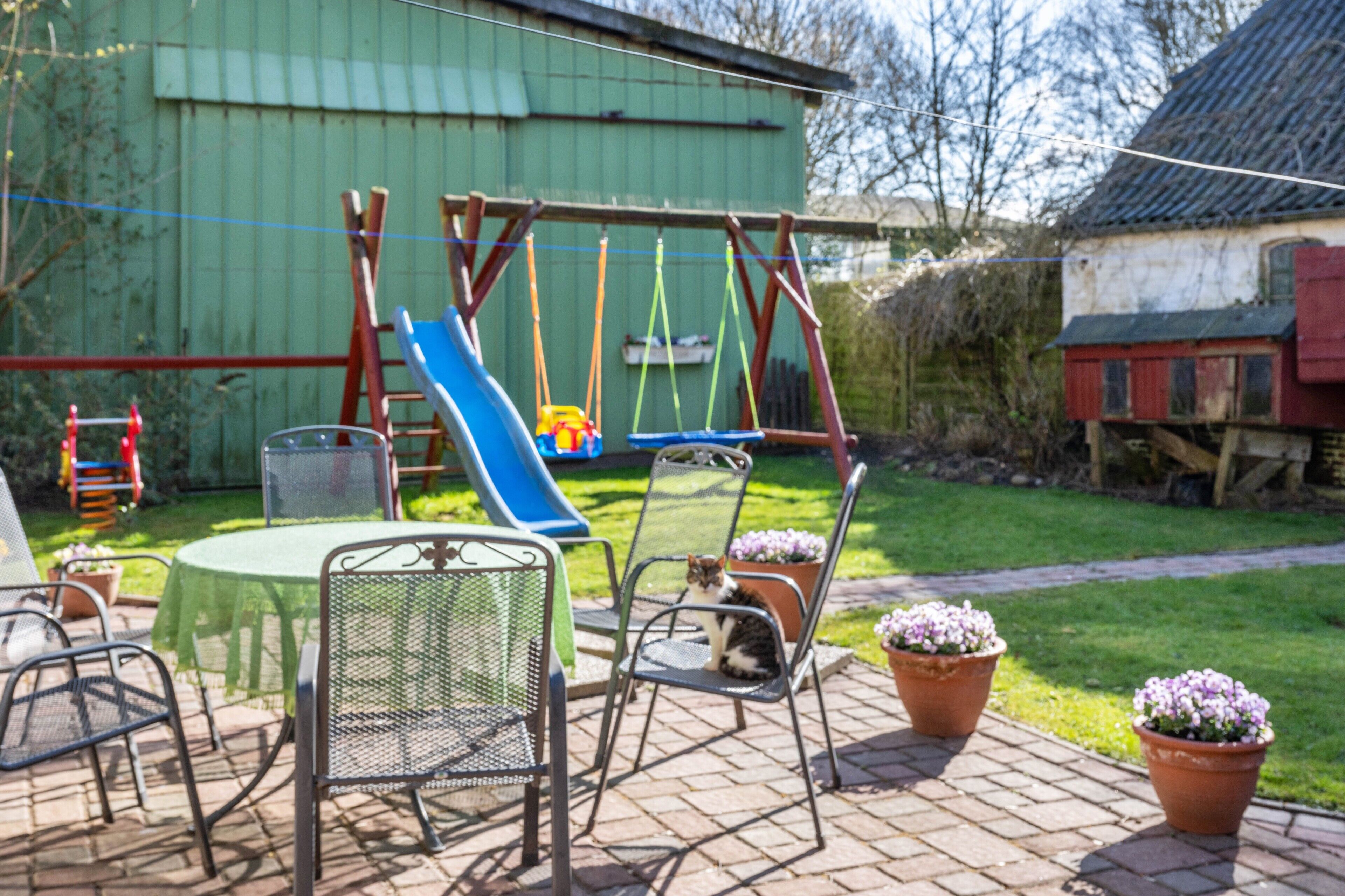 Eine Terrasse mit Gartenmöbeln, einer Schaukel und einer Rutsche.