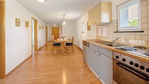 A kitchen with wooden cabinets, a dishwasher, an oven, and a window with a view. - Apartment '1' with Balcony and Wi-Fi (Heroldstatt)