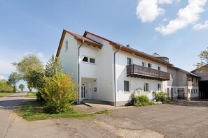Un edificio a due piani con un balcone, un garage e una strada privata.