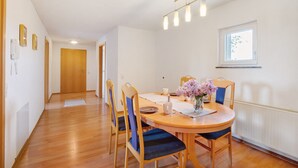 A dining area with a round table, chairs, a vase with flowers, a window, and a door in the background. - Apartment '1' with Balcony and Wi-Fi (Heroldstatt)