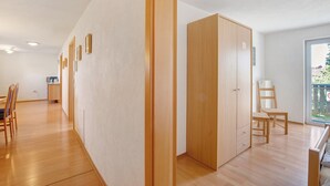 A room with wooden flooring, a wardrobe, a desk with a chair, and a window with a view. - Apartment '1' with Balcony and Wi-Fi (Heroldstatt)