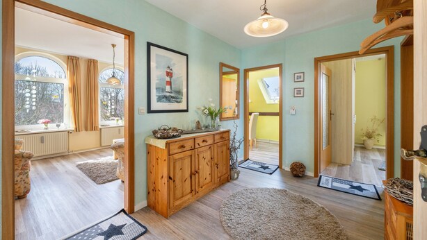 Ein Zimmer mit Holzboden, einem großen Spiegel, einem Holzschrank und einem gerahmten Bild an der Wand.