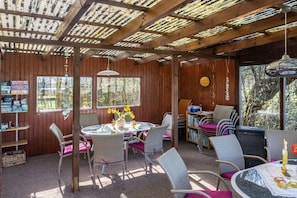 A wooden interior with a round table, wicker chairs, and a bookshelf.