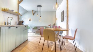 Una cocina moderna con comedor, suelo de madera e iluminación colgante.