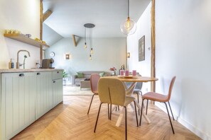 Moderni keittiö, jossa on ruokailutila, puulattia ja riippuvalaisimet.