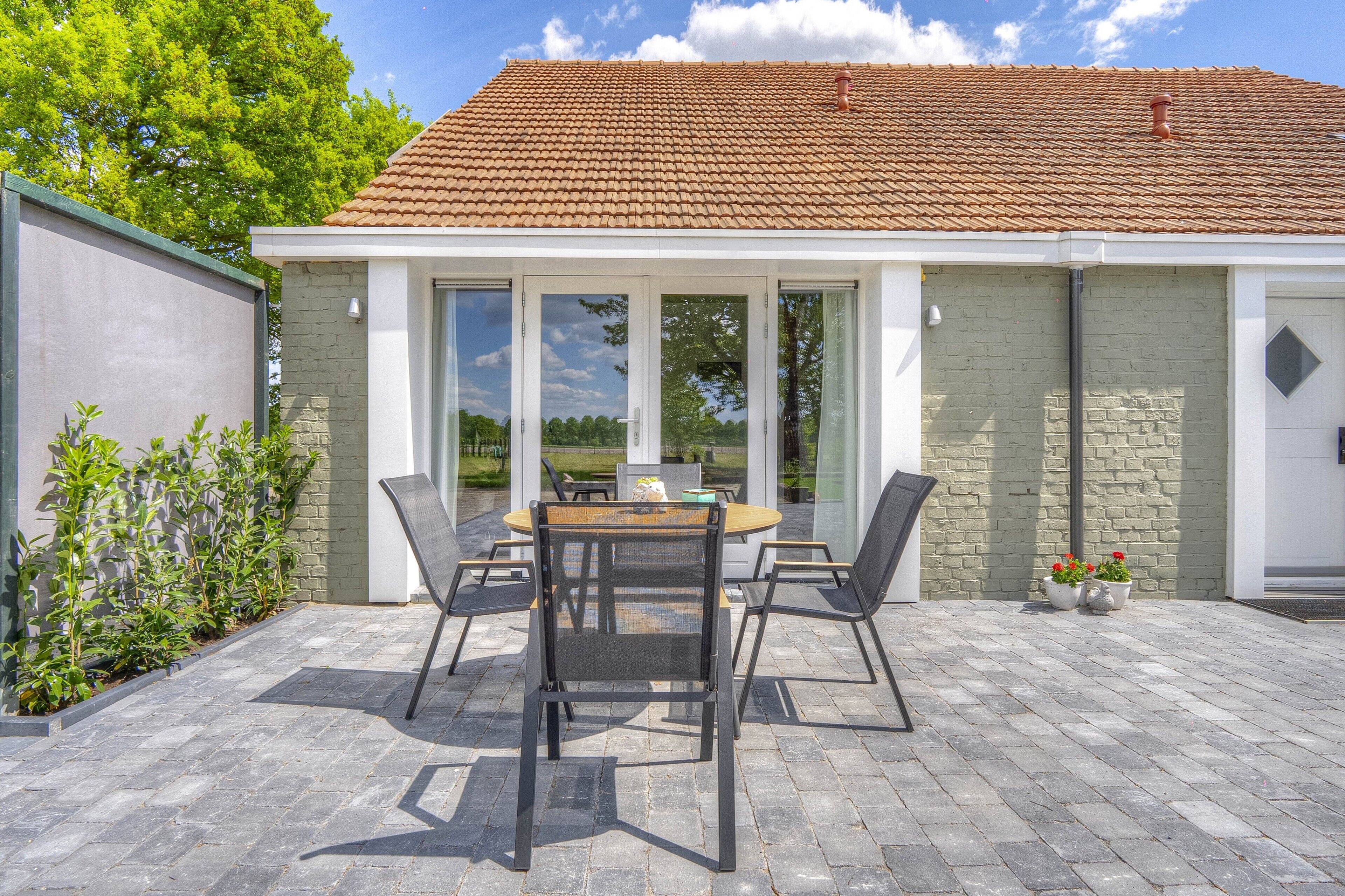 A patio with a table and chairs, a brick wall, and a tiled roof.