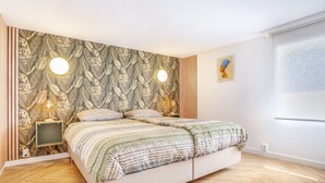 Un dormitorio con una cama, dos luces empotradas, un cuadro enmarcado y una ventana.