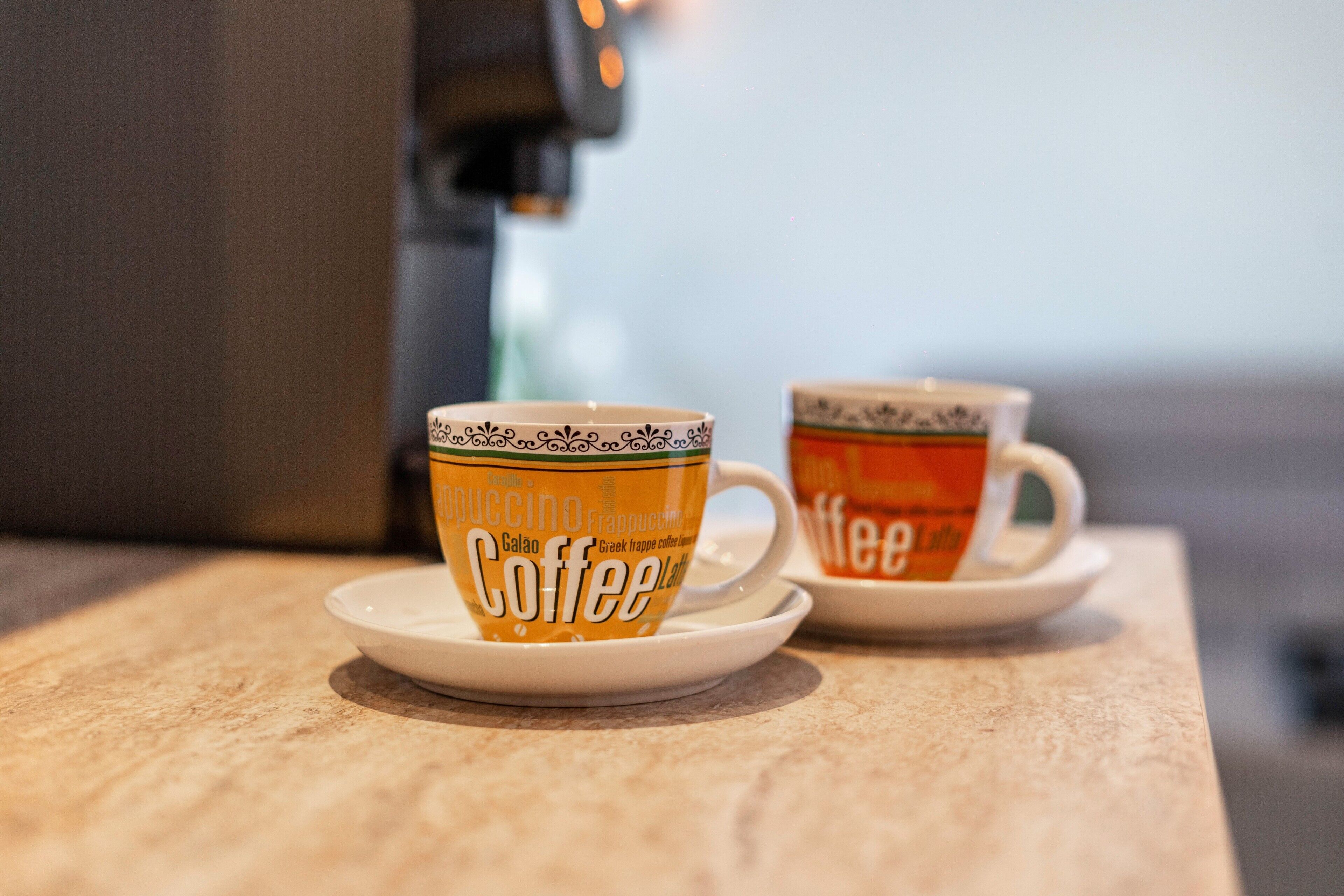 Two coffee cups on saucers with text, placed on a countertop.