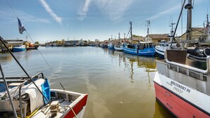 Ein Hafen mit vertäuten Booten, ruhigem Wasser und blauem Himmel.