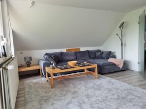 A modern living room with a grey sofa, a wooden coffee table, and a small side table.