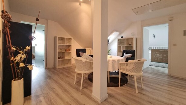 Un loft spacieux avec de hauts plafonds, un coin repas avec une table et des chaises, et une grande fenêtre laissant entrer la lumière naturelle.