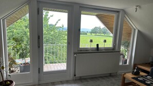 Une pièce avec une grande fenêtre, un radiateur, un banc en bois et une plante en pot.