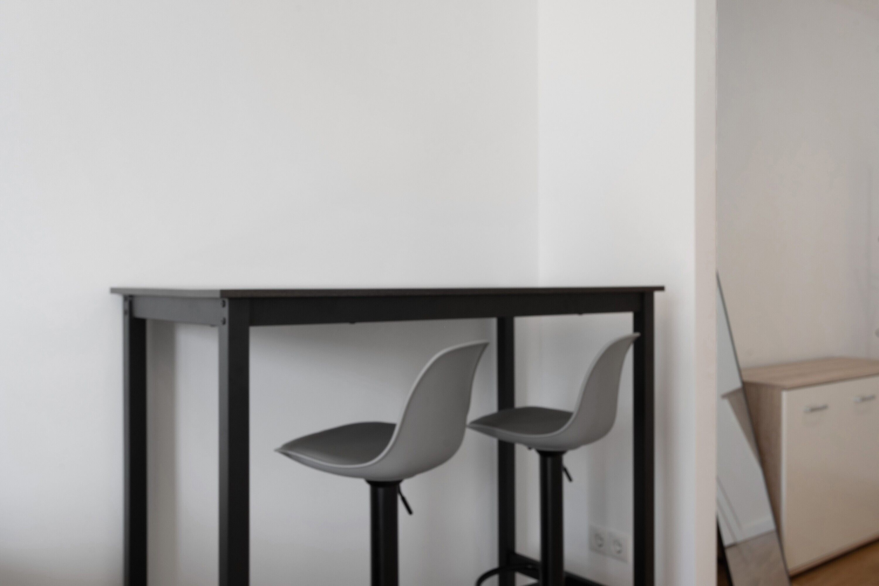 A corner with a black metal table and two grey chairs.