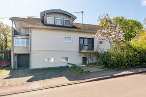 Un immeuble résidentiel de deux étages, doté d’un garage, d’un balcon et d’un petit jardin.