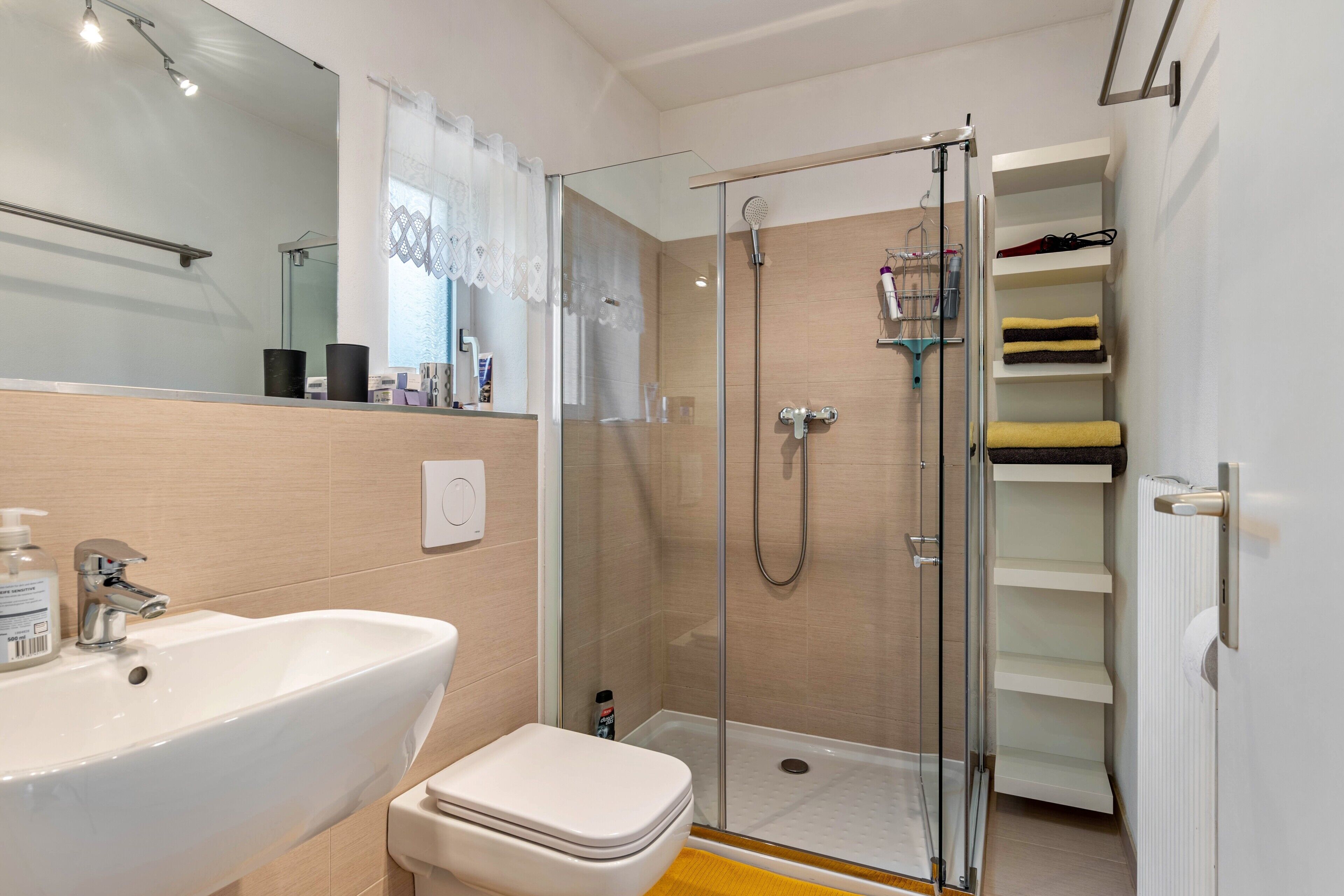 Une salle de bain avec une douche à parois de verre, un lavabo blanc et des toilettes.