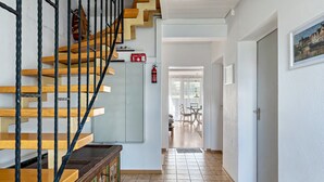 A staircase with wooden steps and black metal railings, a fire extinguisher, and a door leading to a dining area. - Studio 'Jagst' with Shared Terrace and Wi-Fi (Michelbach an der Bilz)