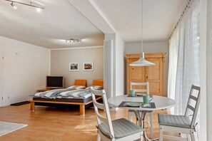 Une chambre à coucher moderne comprenant un lit, une table de chevet, un téléviseur et un coin repas avec des chaises et une table.