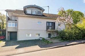 Un immeuble résidentiel de deux étages, doté d’un garage, d’un balcon et d’un petit jardin.