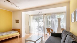 A modern living room with a sofa, a bed, a table, and a chair.