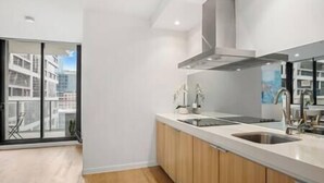 Une cuisine moderne avec des meubles en bois, des appareils en acier inoxydable et une grande fenêtre donnant sur la ville.